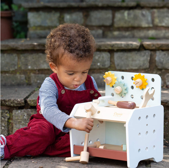 Baby playing with Classic World wooden activity toy