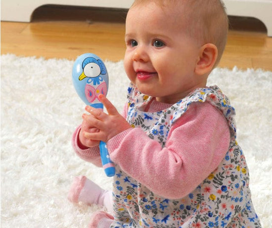 Baby girl holding Orange Tree wooden peter rabbit maracas toy