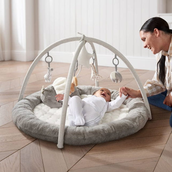 Baby laying down on grey Mamas & Papas playmat