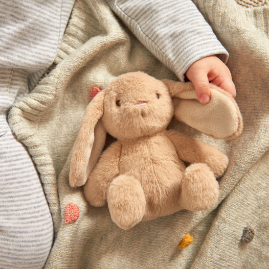 Baby holding Mamas & Papas bunny ear toy