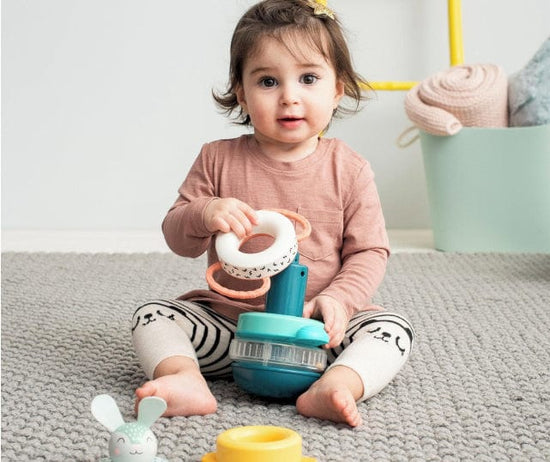 Baby girl playing with taf toys wooden stacker